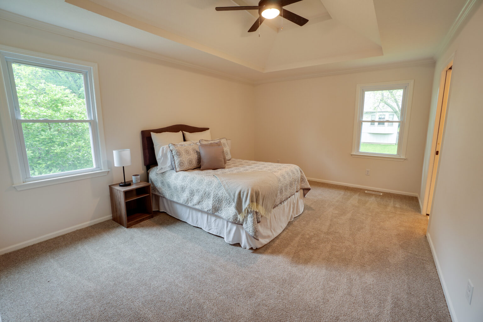 a bedroom with a big bed, a nightstand, and two windows