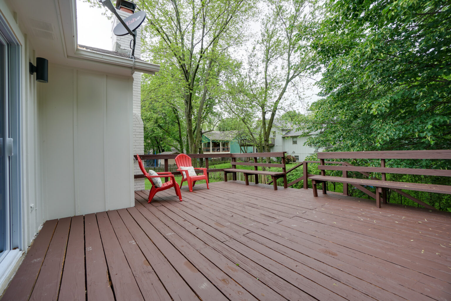 a patio with two red chairs and benches