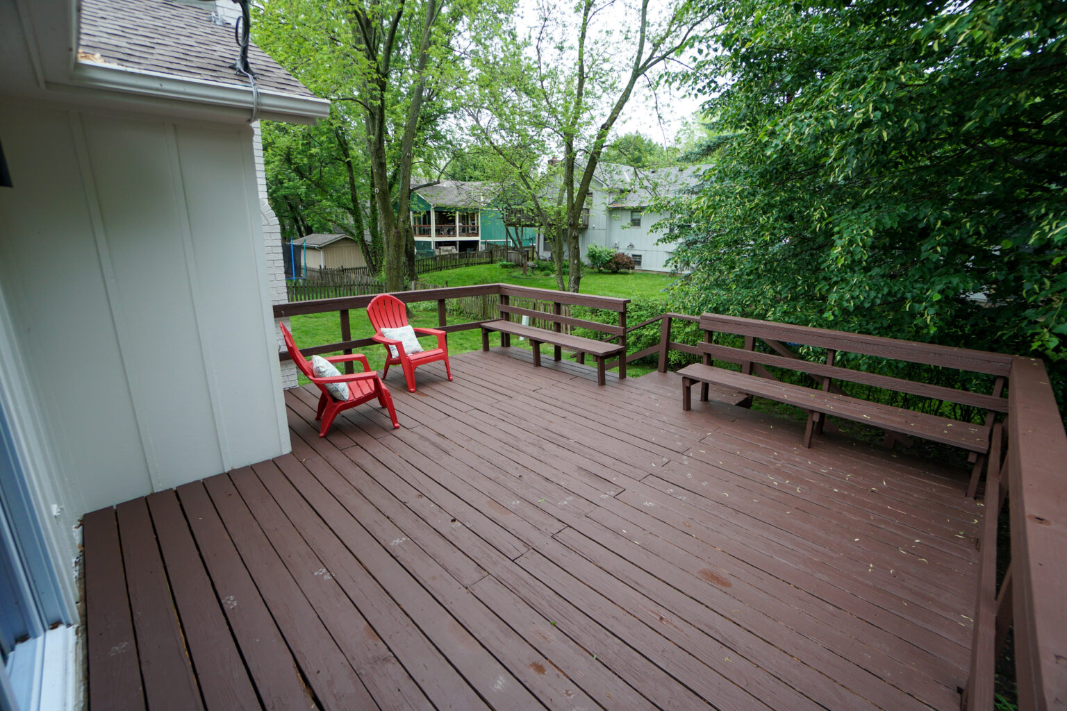 a patio with two red chairs and benches 2